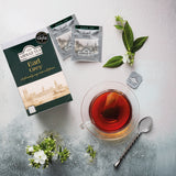 Ahmad Tea Earl Grey 20 Teabags - Box with envelops next to hot cup of tea